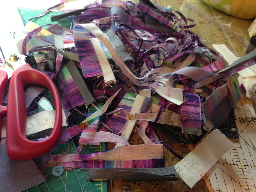 Purple fabric scraps piled on cutting mat